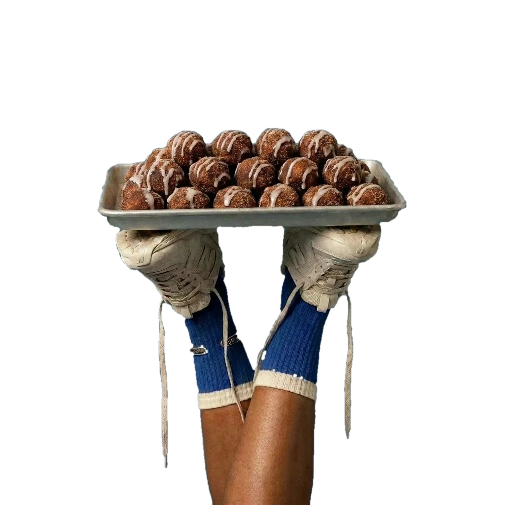 a tray of iced cinnamon bites held up by two sneakers, legs in the air, cut out like a sticker
