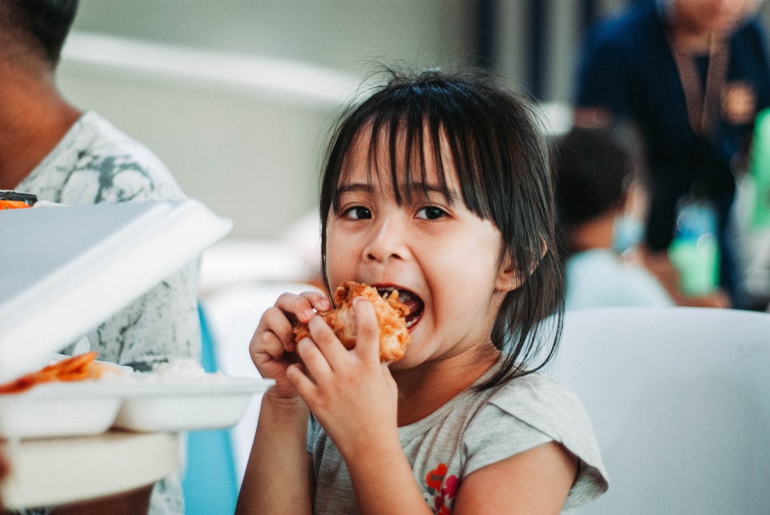 a kid grinning over a sandwich